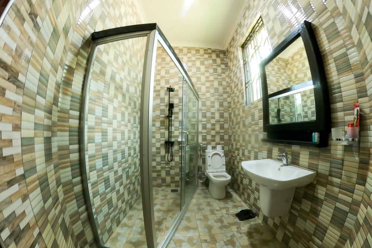 A bathroom with a glass shower enclosure, a toilet, and a sink.