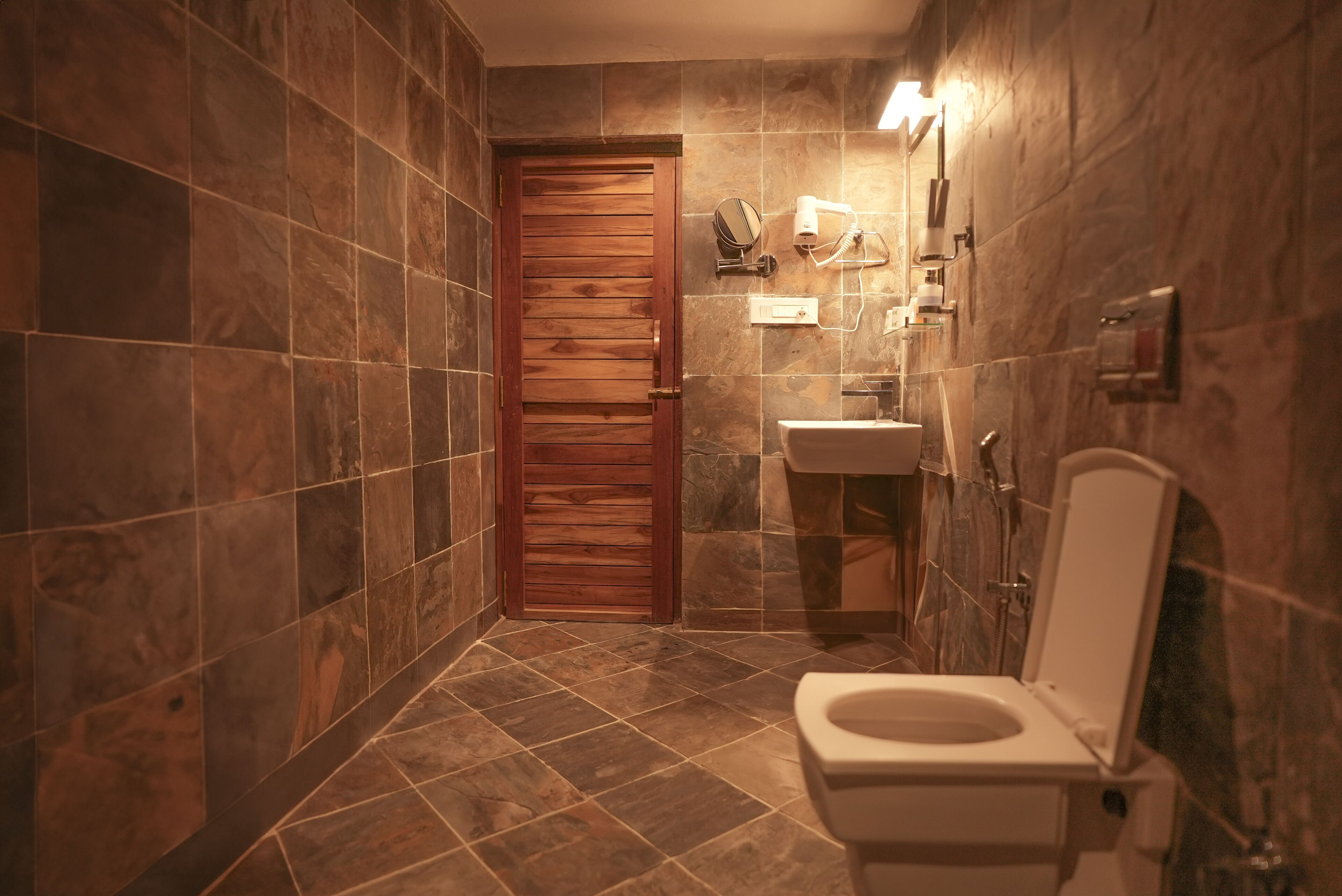 A bathroom with a wooden door, a sink, and a toilet.