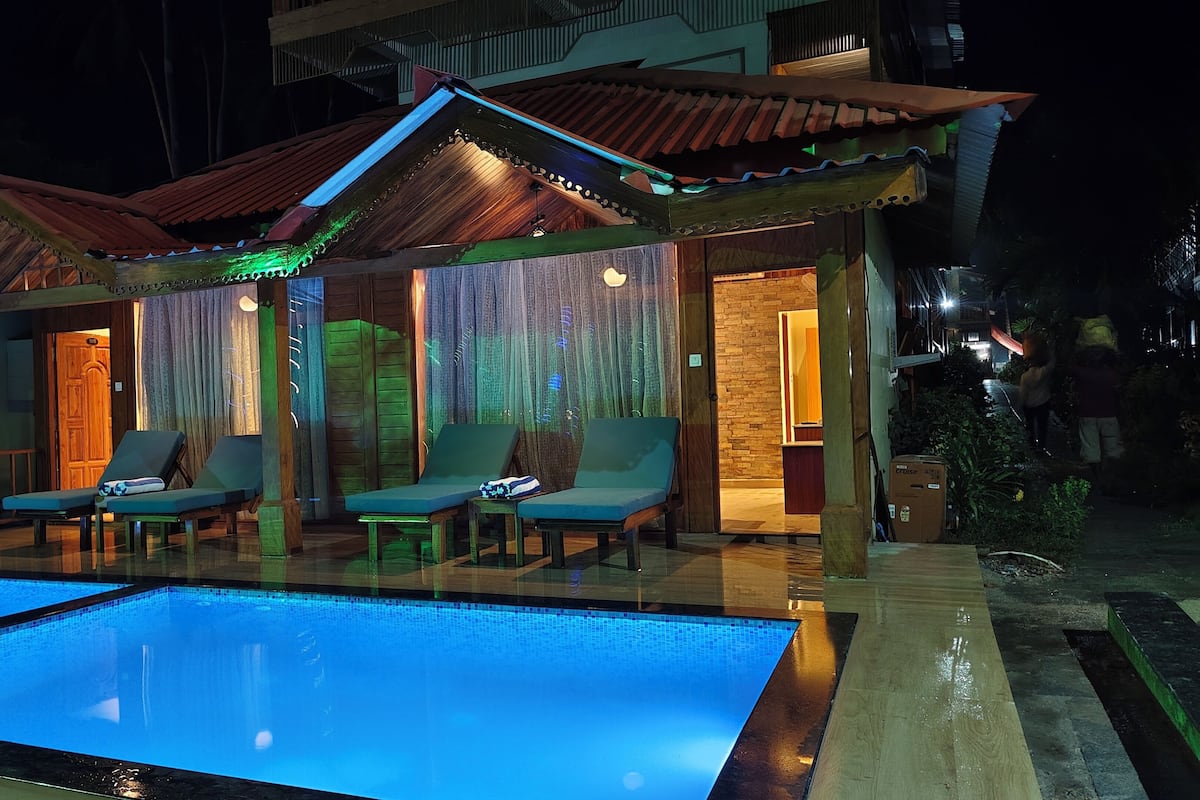 Uma área à beira da piscina com espreguiçadeiras e piscina.