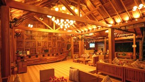 Un mostrador de recepción con forma de barco de madera, paredes de madera y un rincón de estar acogedor con sofás y una mesa de centro.