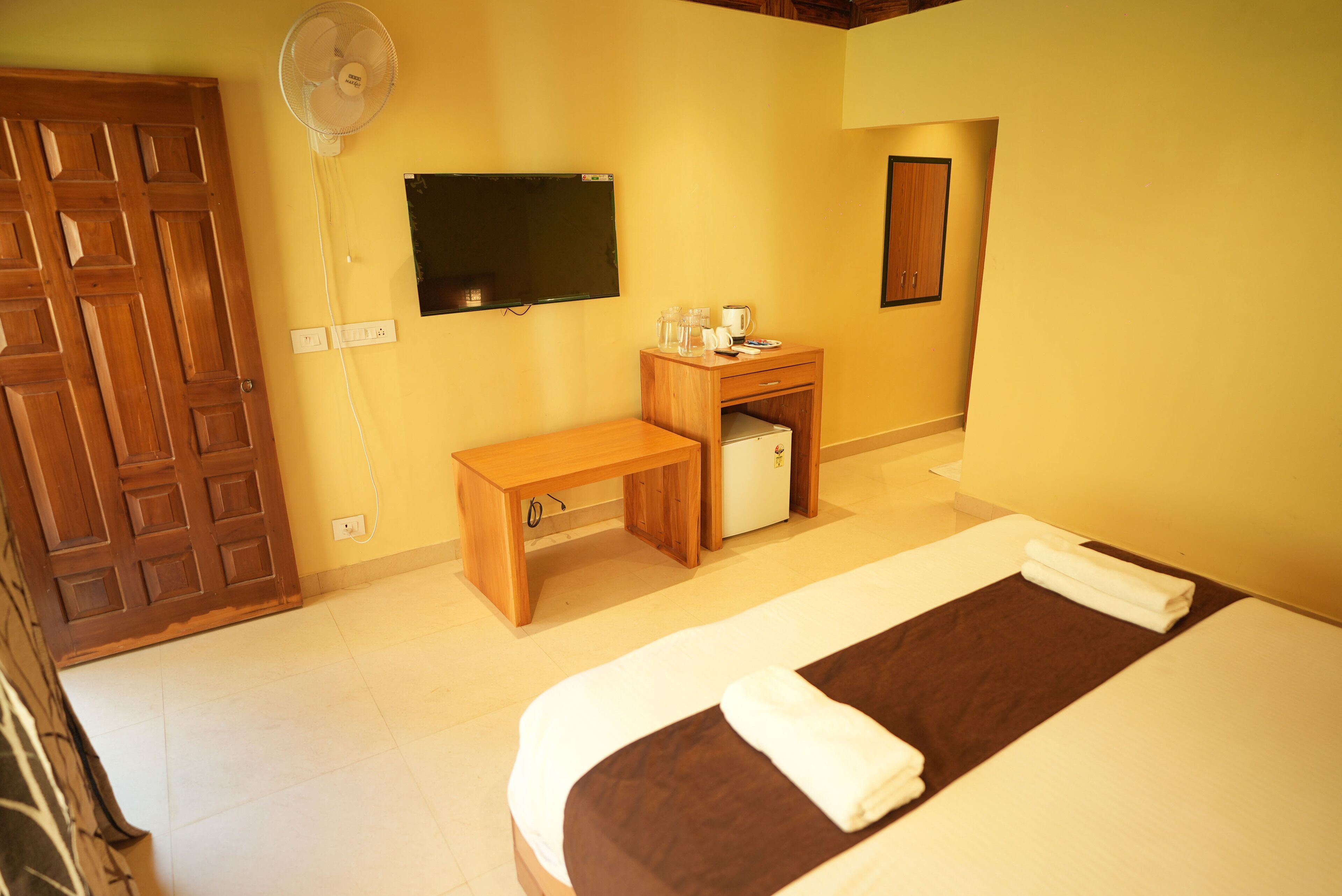 Una habitación de hotel con cama, escritorio, silla, televisión y armario.