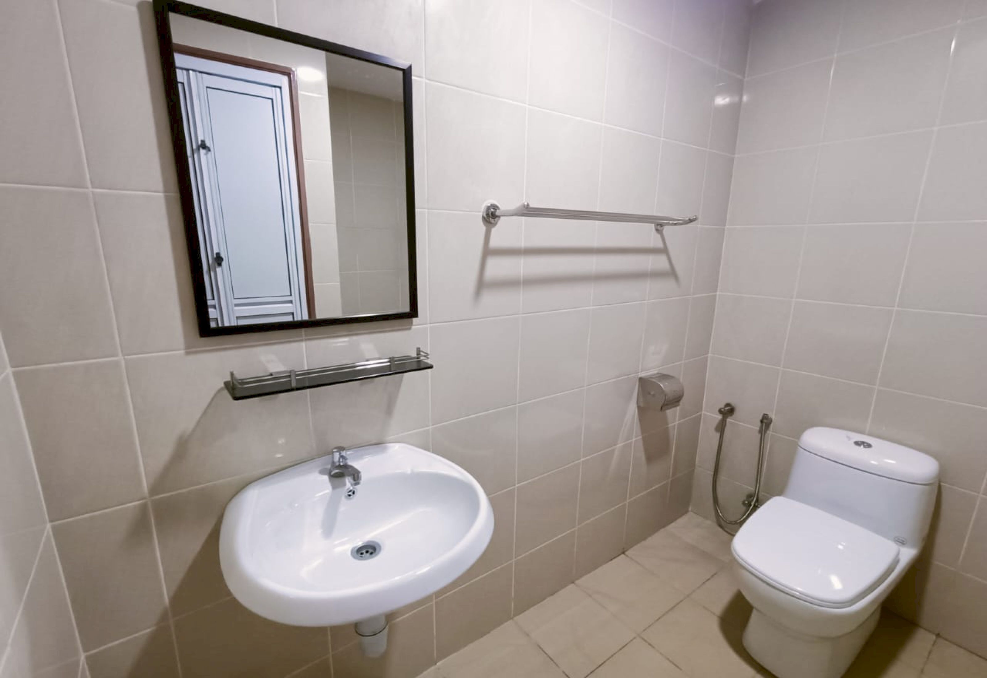 Un baño con un lavamanos blanco, un inodoro, un perchero para toallas y un espejo.