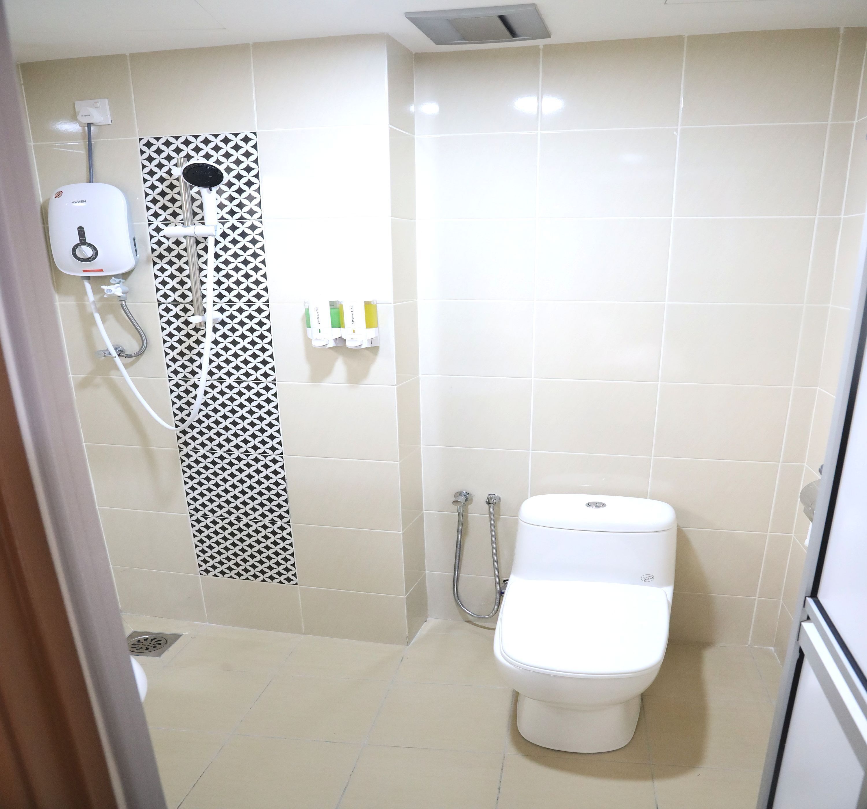 A small, modern bathroom with a toilet, a shower, and a hand dryer.