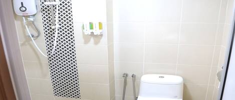 A small, modern bathroom with a toilet, a shower, and a hand dryer.
