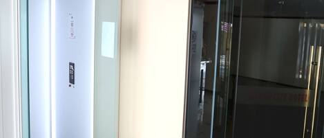 A hotel room with a glass door, a control panel, and a sign indicating "Do Not Enter."