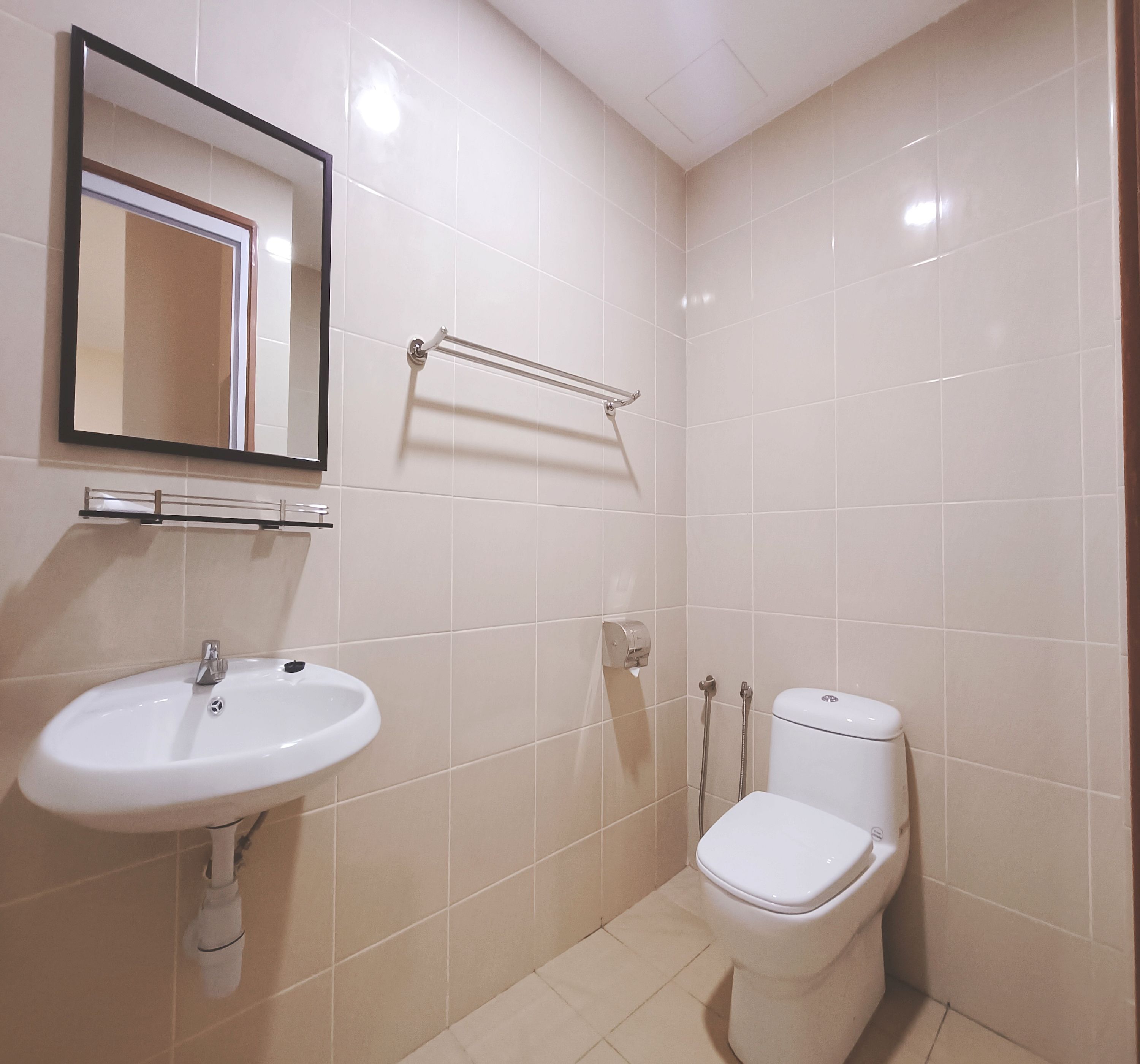 A small, clean bathroom with a white sink, mirror, and toilet.
