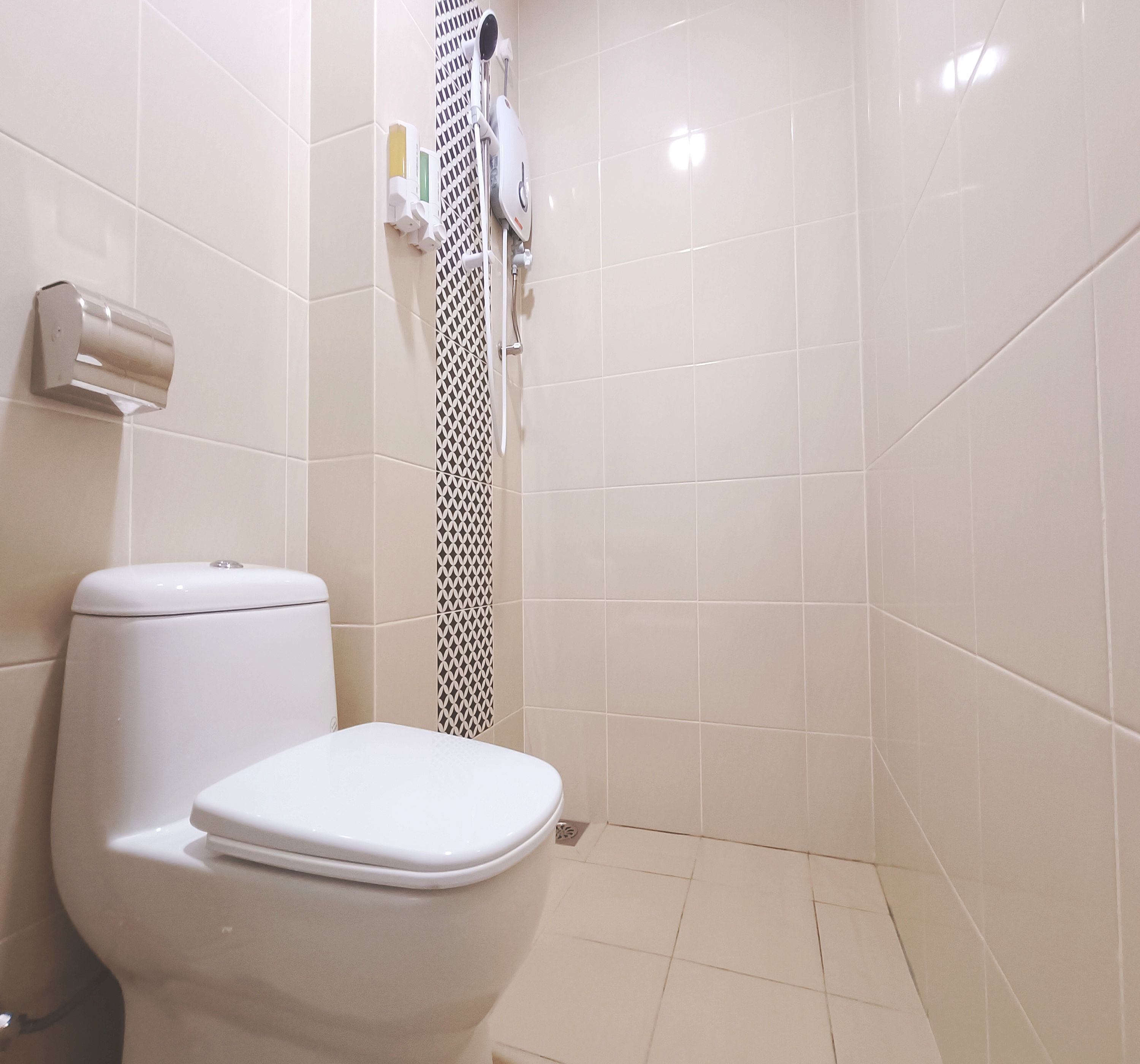 A bathroom with a toilet, a shower, and a hand dryer.