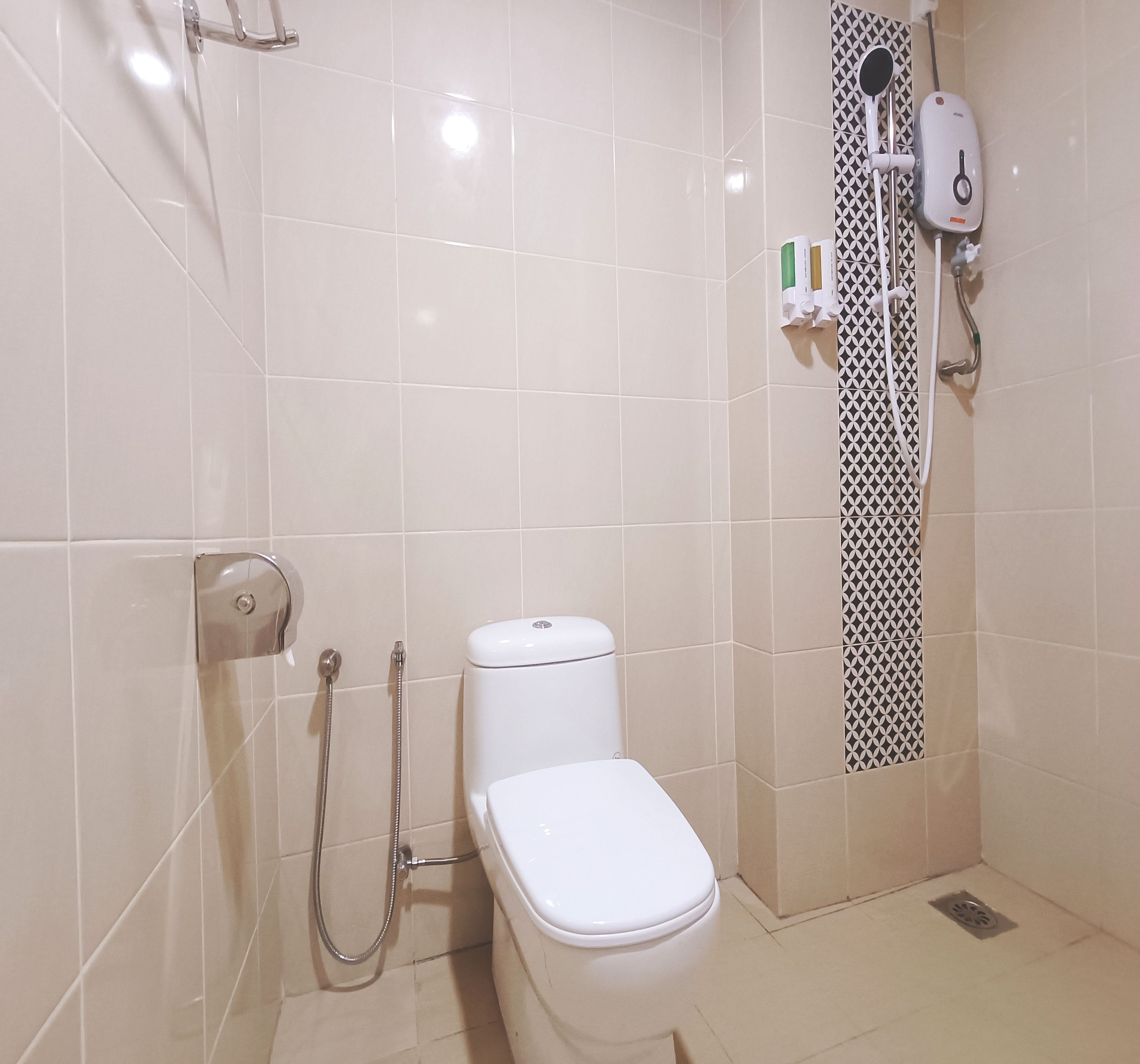 A small, clean bathroom with a toilet, a shower, and a hand dryer.