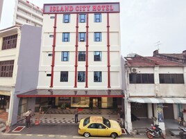 Un hotel con fachada roja y blanca, múltiples ventanas y una entrada a cuadros.