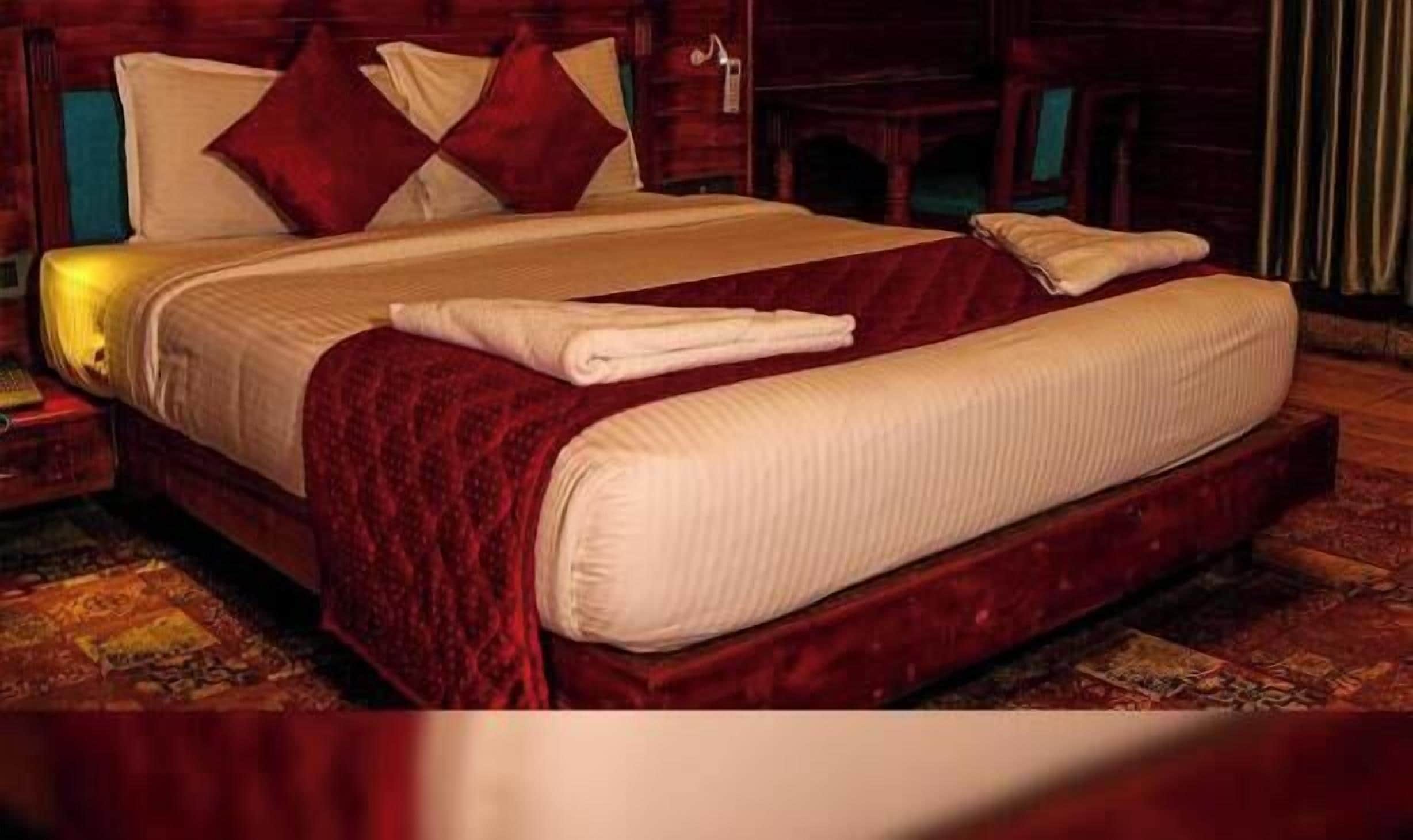 A bed with a red headboard, white bedding, and a red throw blanket.