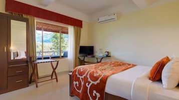 A bedroom with a bed, a desk, a TV, and a window with a view.