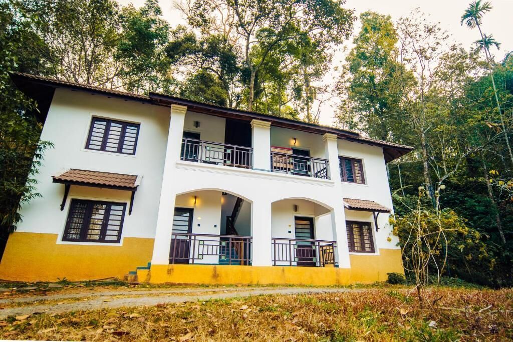 A two-story building with balconies, a staircase, and a surrounding natural landscape.