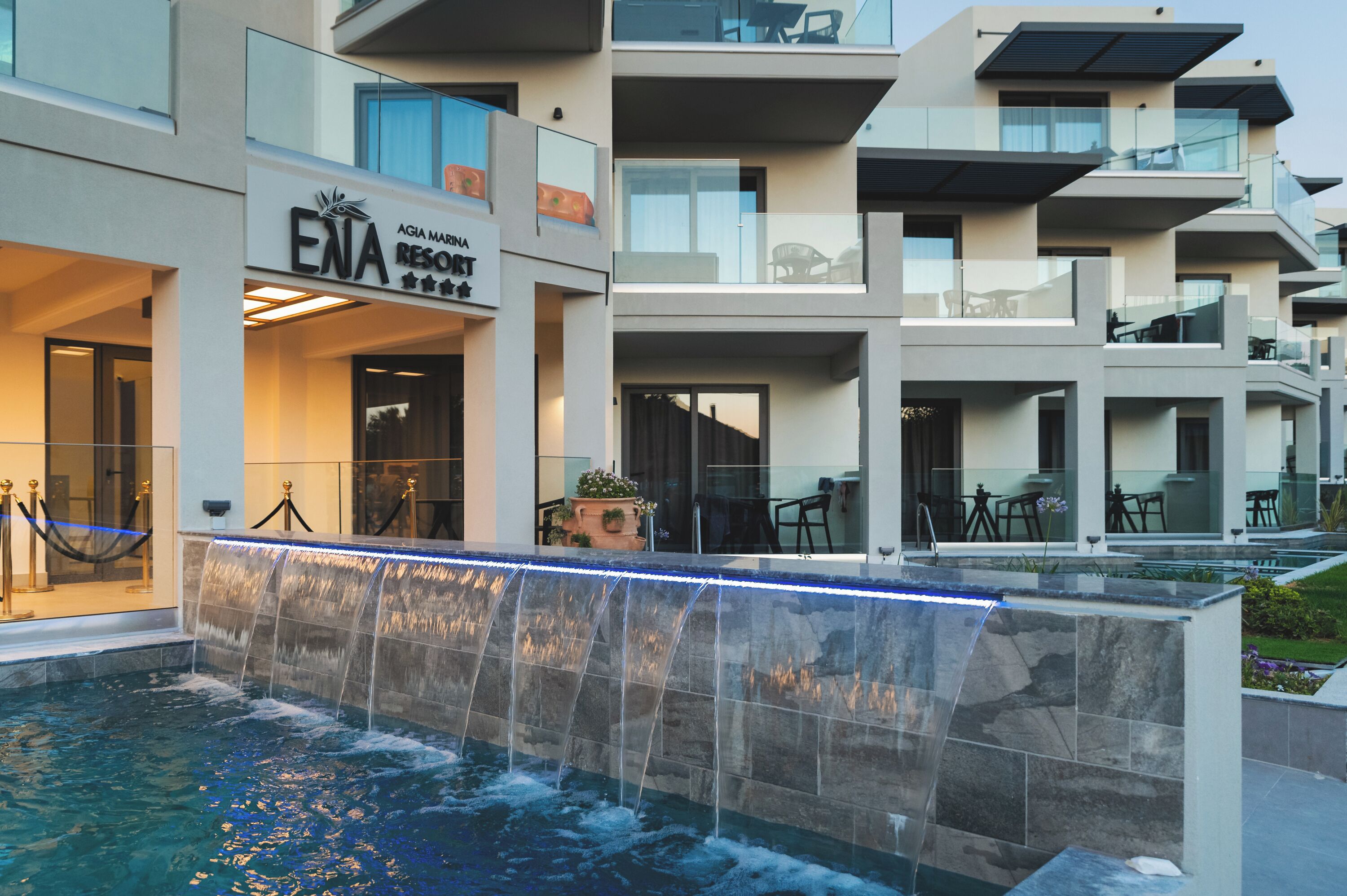 A modern hotel with a pool area, outdoor seating, and a sign for "ENA Resort."