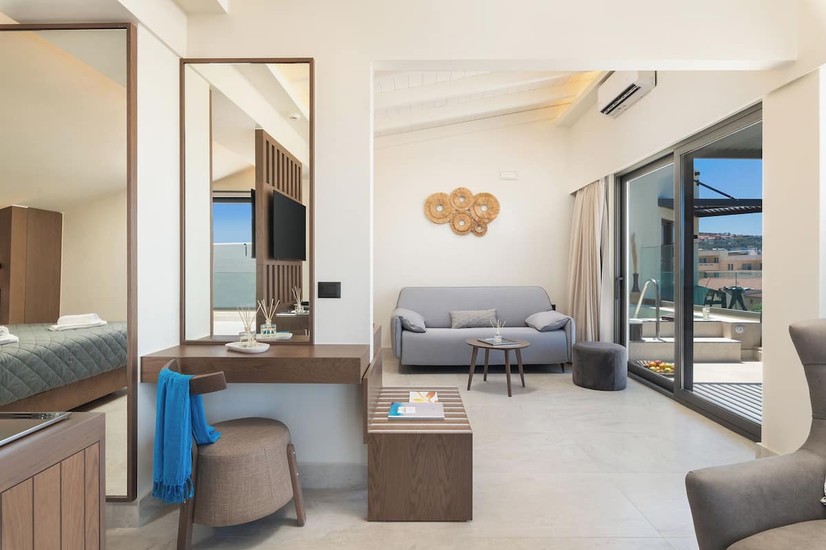 Une chambre d’hôtel moderne équipée d’un lit, d’un canapé, d’une table basse et d’une grande fenêtre donnant sur la ville.