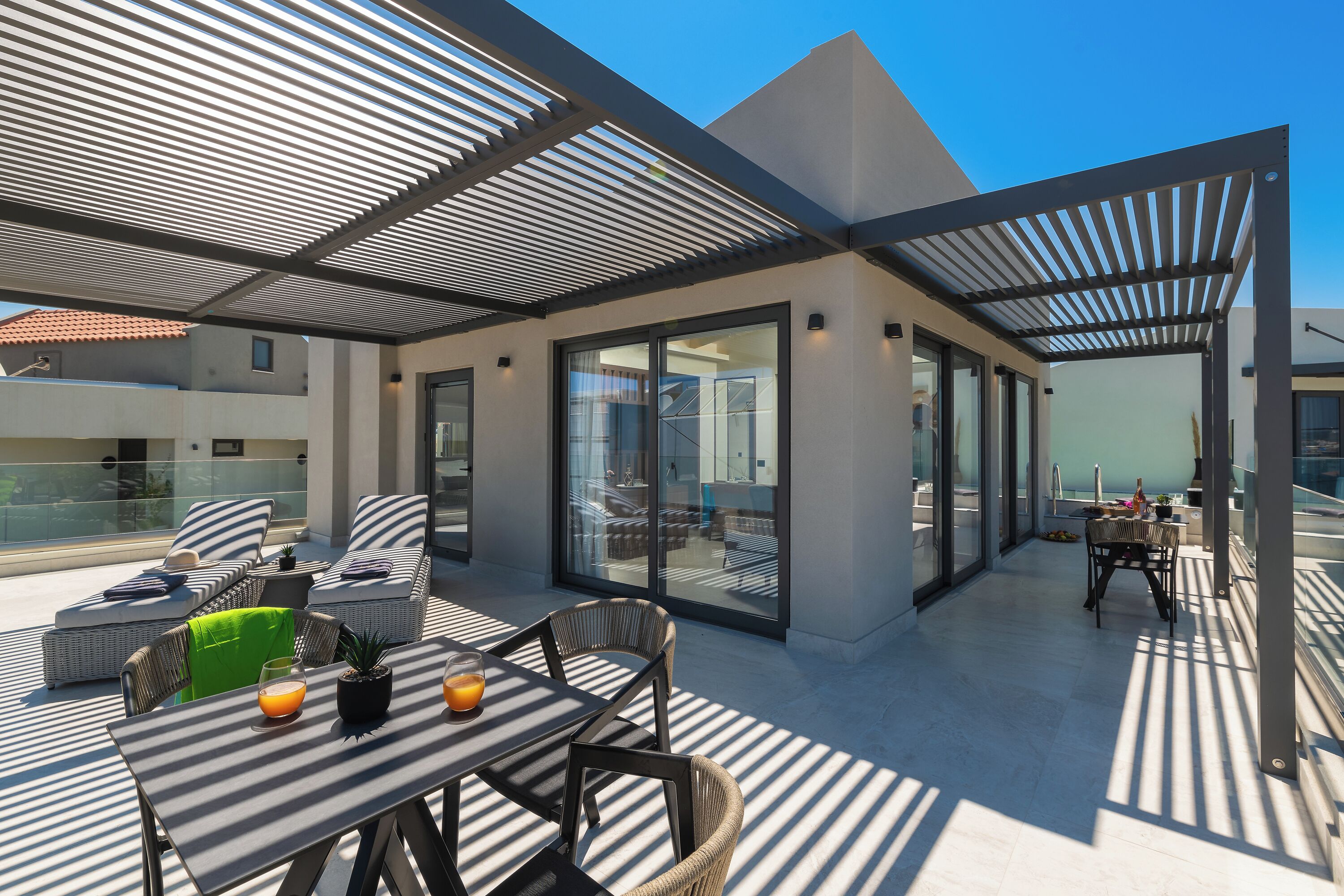 A rooftop terrace with outdoor seating, a table with drinks, and a view of the city.