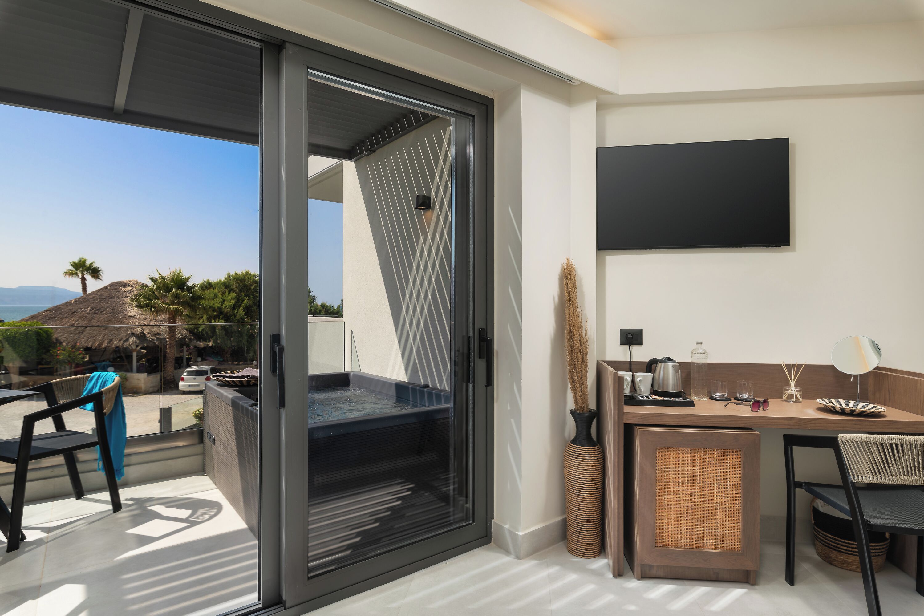 Una habitación moderna con puerta de vidrio corredera que da a un balcón, una kitchenette pequeña, televisor de pantalla plana y vistas al paisaje.