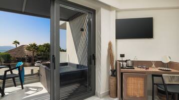 Una habitación moderna con puerta de vidrio corredera que da a un balcón, una kitchenette pequeña, televisor de pantalla plana y vistas al paisaje.
