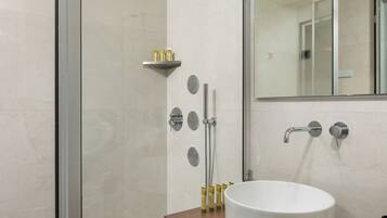 A modern bathroom with a glass-enclosed shower, a white sink, and a wooden vanity.