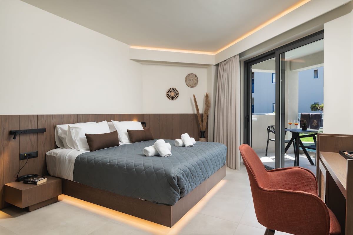 Une chambre d’hôtel moderne, dotée d’un grand lit, d’un bureau et offrant une vue sur l’extérieur.