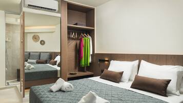 A hotel room with a bed, a wardrobe, a mirror, and a shower.