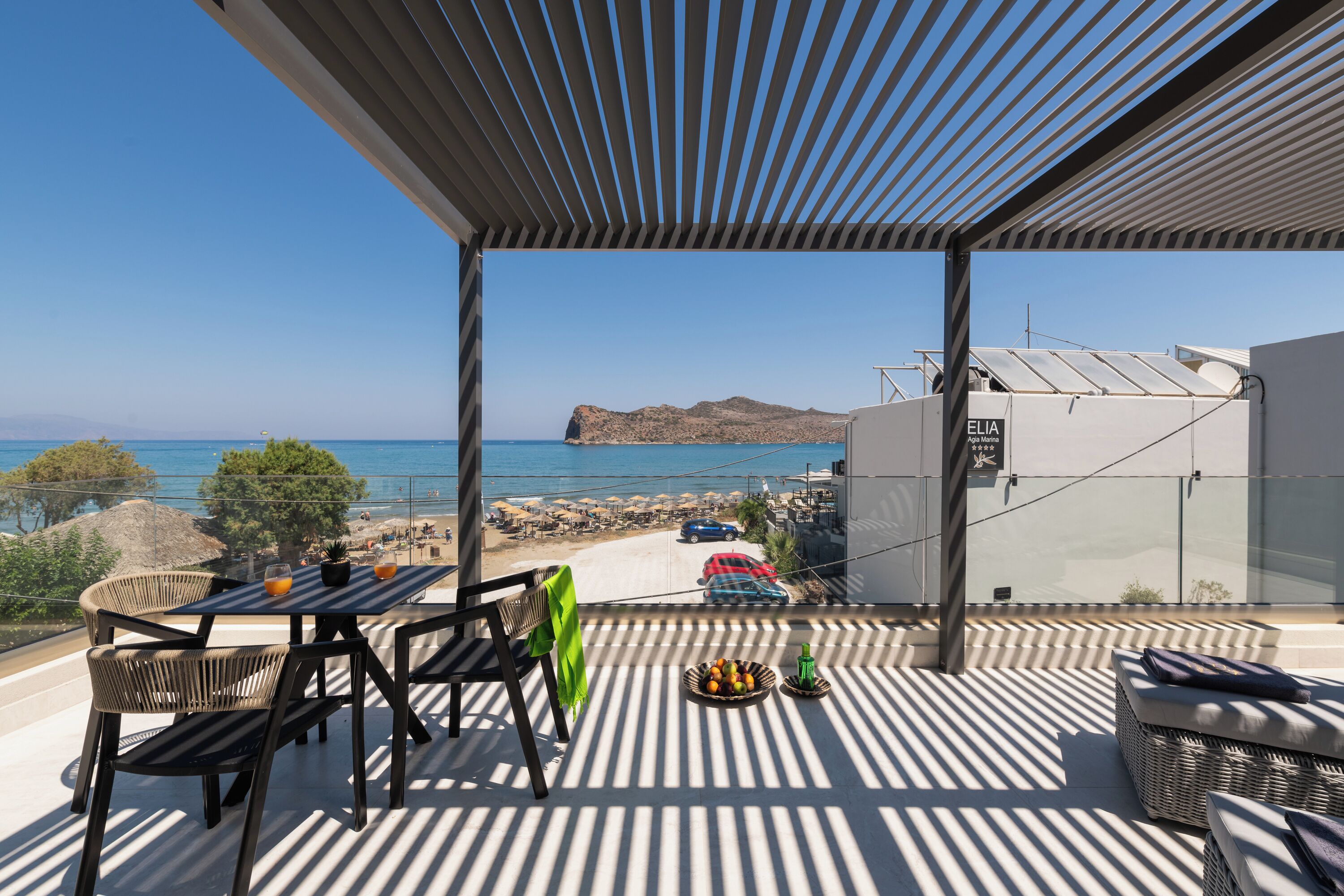 Un balcón con vistas al mar, una mesa con sillas y una cesta de fruta.