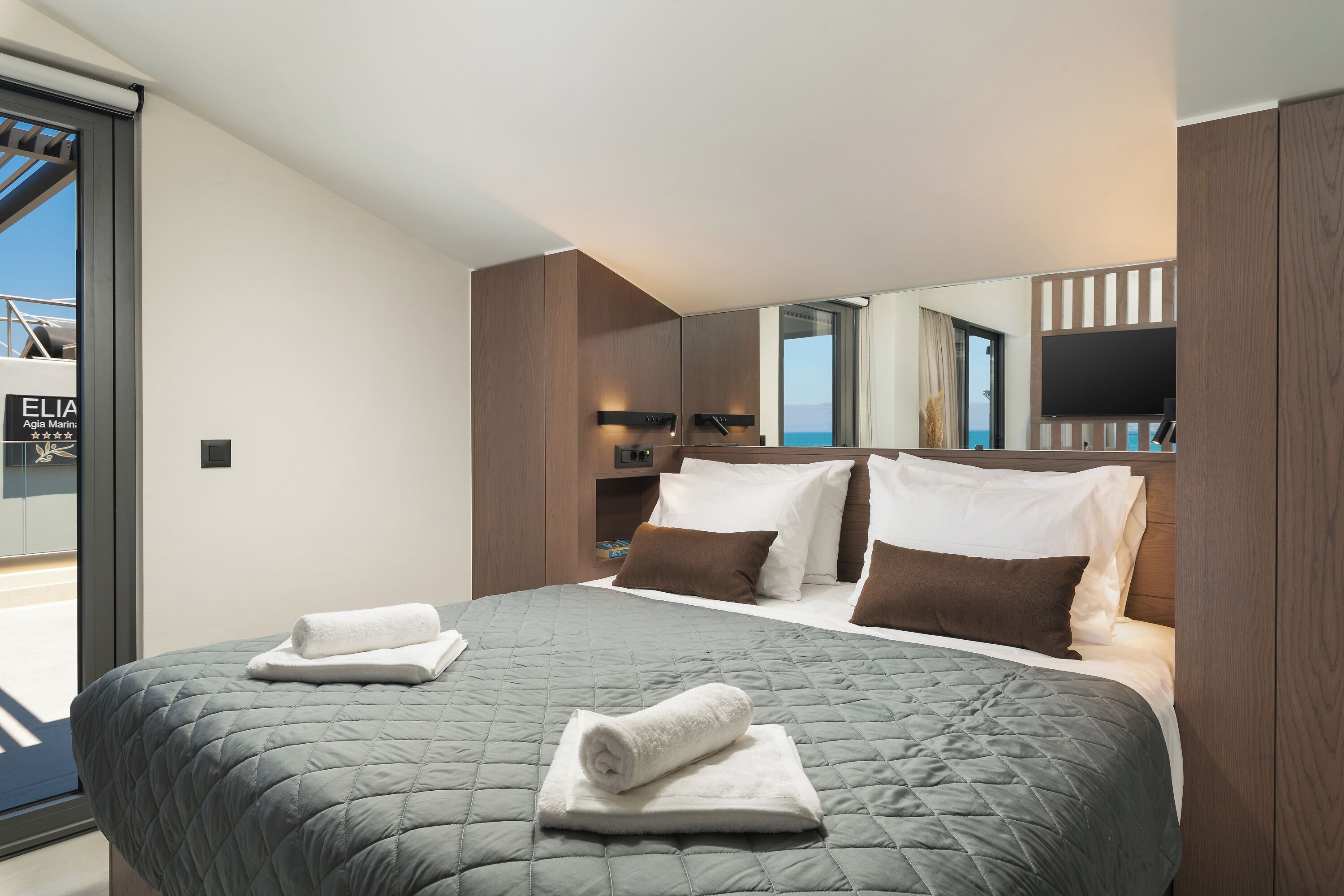 Un dormitorio moderno con una cama grande, televisión y vista al mar.