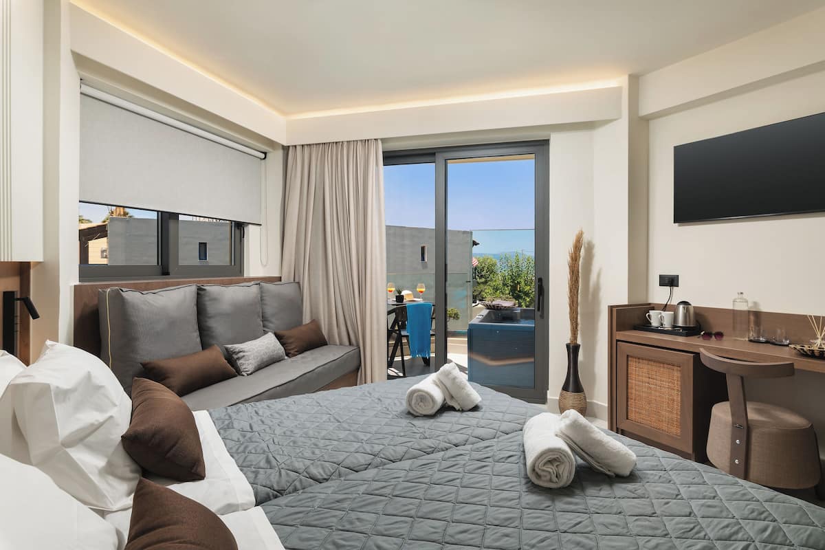 Une chambre d’hôtel avec un grand lit, un bureau, une télévision et un balcon équipé d’une table et de chaises.