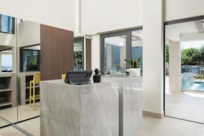Un espace d’accueil moderne avec un comptoir en marbre, un ordinateur portable, une imprimante noire et une plante en pot.
