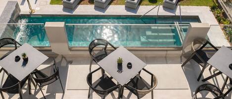 Zona de piscina en la azotea con sillones de descanso y mesas, rodeada por un muro bajo y plantas en macetas.