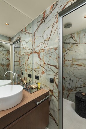 Une salle de bain avec un mur en marbre, un lavabo et un miroir.