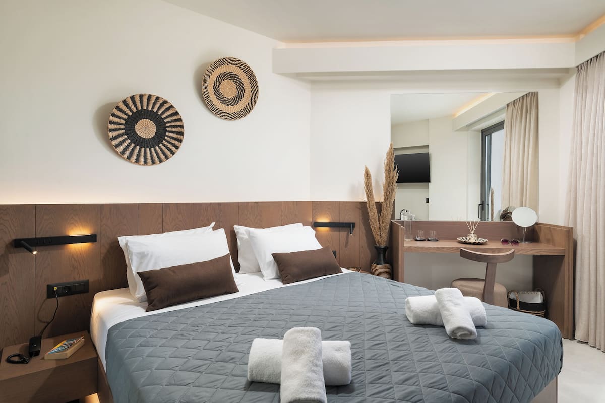 Une chambre d’hôtel comprenant un lit, une table de chevet, une œuvre d’art accrochée au mur, un miroir et un espace salle de bain.