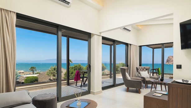 Een moderne woonkamer met een grote schuifpui naar een balkon met uitzicht op zee.