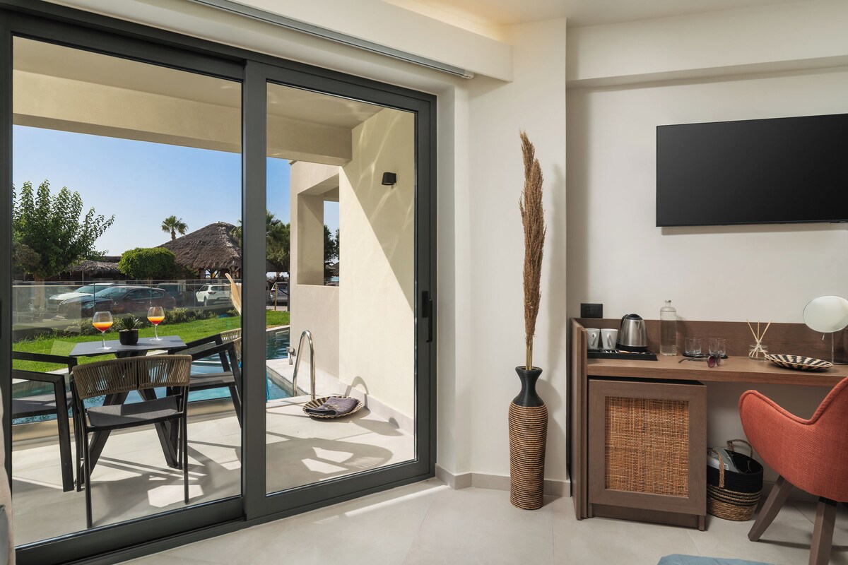 A modern room with a sliding glass door leading to a pool area, a flat-screen TV mounted on the wall, and a small desk with a chair.