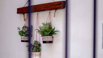 A wall-mounted wooden shelf with three hanging planters containing green plants.