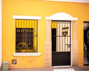 Un edificio amarillo con una verja negra y una ventana con reja de metal.