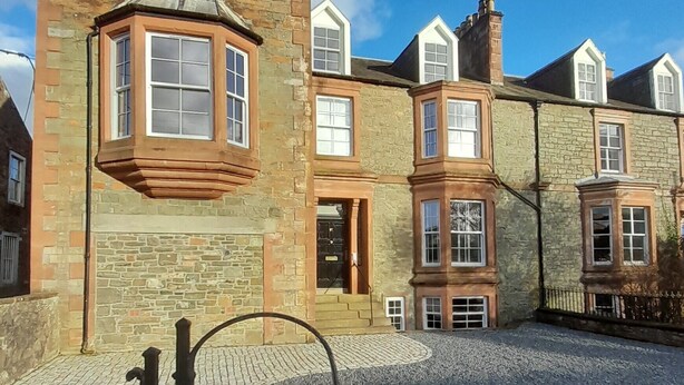 A stone building with a prominent corner window and a plaque reading "Mansefield House."