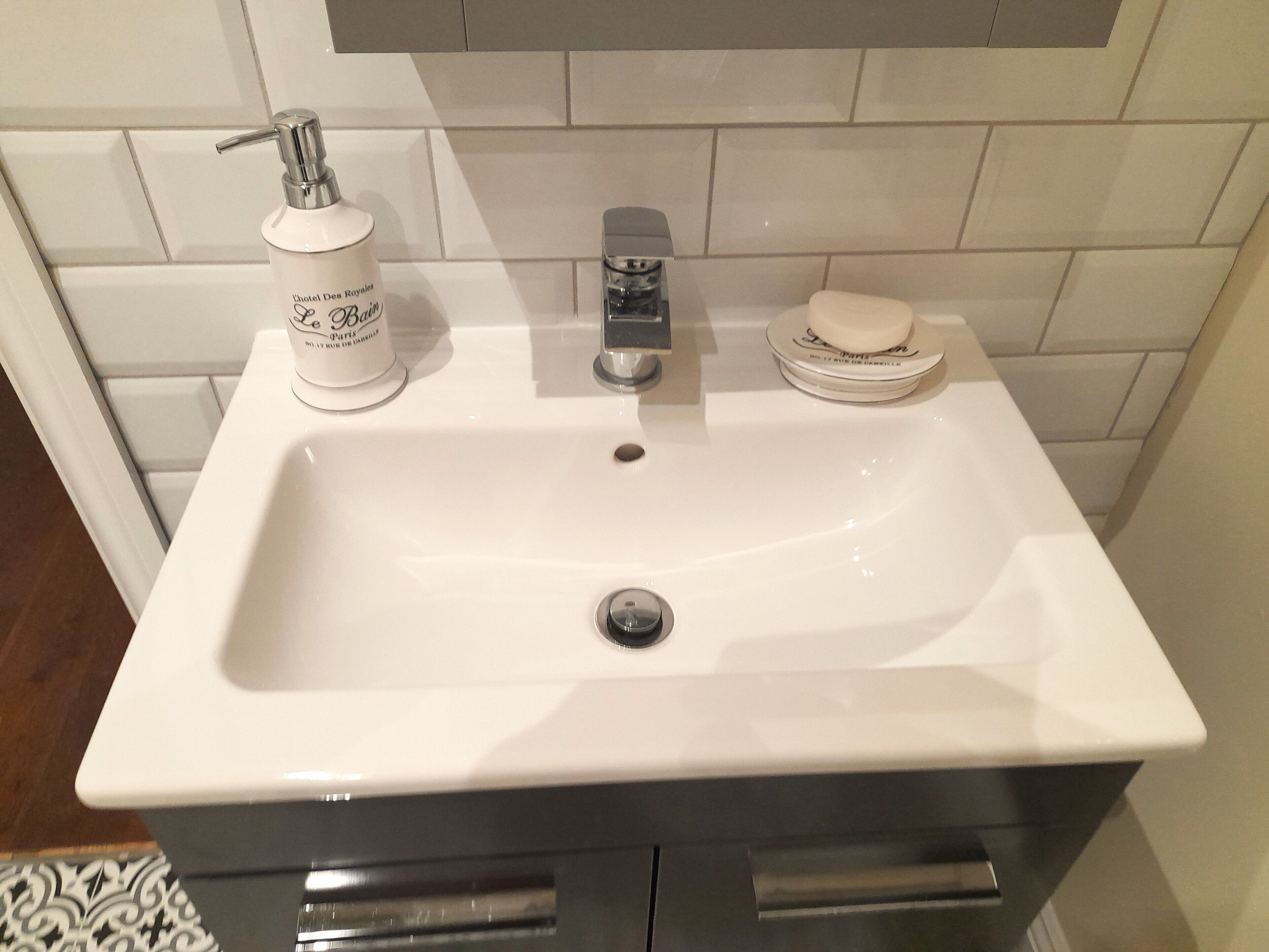Un lavabo de salle de bain avec un robinet, un distributeur de savon et un porte-savon.