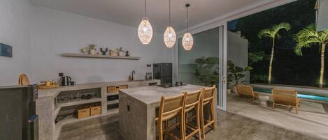 A modern kitchen with a central island, bar stools, and pendant lighting.