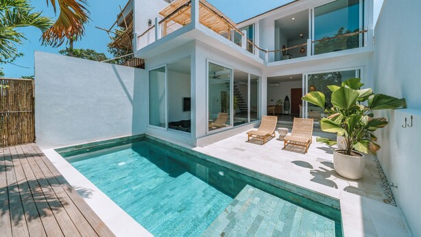 A modern two-story house with a swimming pool, large glass windows, and a wooden deck. - Villa Seseh Breeze (Cemagi)