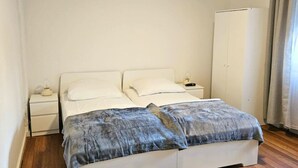 Une chambre à coucher comprenant un lit, deux tables de chevet, une armoire et une petite table de nuit.
