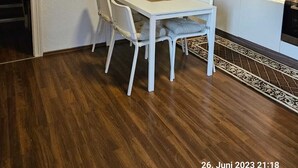 Une cuisine moderne avec des meubles blancs, un coin repas doté d’une table et de chaises blanches, et un tapis à motifs sur le sol.