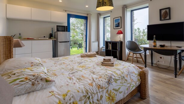 Une chambre à coucher comprenant un lit, un bureau, une chaise, un téléviseur et une vue sur l’extérieur.
