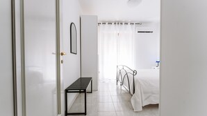 Un dormitorio con cama, un banco y una puerta que da a otra habitación.