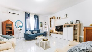 Una sala de estar moderna con un sofá azul, una mesa de centro blanca y un mueble para televisión.