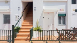 Un edificio con una scala che conduce a un ingresso, una porta con il simbolo del numero e una finestra con persiana.