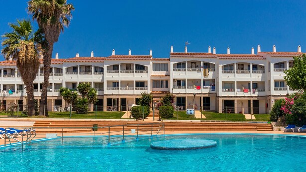 Un hotel con piscina, diversi balconi e palme.