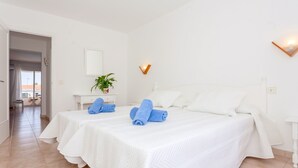 Camera d'albergo con due letti, un tavolino con una pianta e un punto luce a parete.
