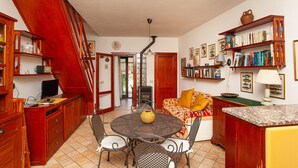 Una cocina con comedor, armarios de madera, una escalera y una estantería.