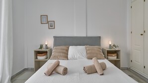 Ein ordentlich bezogenes Bett mit zwei Kissen, zwei Nachttischen mit Lampen und zwei Wandbildern.