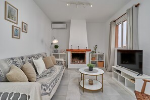 A modern living room with a sofa, TV, fireplace, and decorative items.